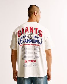 a man standing in front of a white wall wearing a t - shirt that says giants super bowl champs