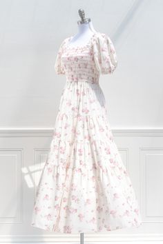 A stunning floral dress, the Belle Époque maxi features a beautiful pink floral print on cream cotton, breezy full skirt, square neckline, puffed sleeves, and a smocked elastic bodice for a comfortable, flattering fit. Pair it with a woven sunhat for a romantic fairytale look! . Details: S: Bust 26"-37", Waist 26"-32", Length: 48" M: Bust 28"-39", Waist 28"-34", Length: 49" L: Bust 30"-41", Waist 30"-36", Length: 50" Length Waist to Hem: 36" Lined Material: 100% Cotton Lining: 100% Rayon Hand Wa Floral Print Square Neck Maxi Dress For Daywear, Pink Floral Print Maxi Dress With Puff Sleeves, Floral Square Neck Dress With Smocked Bodice, Pink Puff Sleeve Smocked Dress For Garden Party, Pink Smocked Dress With Puff Sleeves For Garden Party, Feminine Ruched Square Neck Maxi Dress, Pink Floral Print Maxi Dress With Square Neck, Summer Floral Dress With Square Neck And Gathered Sleeves, Cotton Smocked Dress With Square Neck