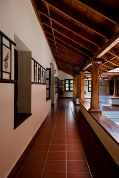 an empty hallway with columns and pictures on the wall, along with tiled flooring