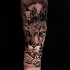 a man's arm with a lion and mountain scene tattoo on the left forearm