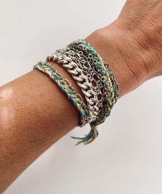 A multiple chain bracelet mixed with a 100% cotton multi colored thread braid. The chains are a mix of a large rhodium plated steel chain, small silver plated brass link & figaro chains, and tiny silver plated brass chains. The braided thread colors are dusty blues, aqua, lime, green tea, peach, and cream. The total length of the bracelet is 7.5" and it has a silver plated brass trigger clasp. Details: Multiple chain bracelet with braided thread detail. 100% cotton thread in dusty blues, aqu Layered Silver Bracelets, Peach And Cream, Thread Colors, Figaro Chains, Layered Bracelets, Brass Chain, Steel Chain, Cotton Thread, Chain Link Bracelet