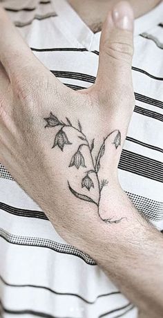 a man's hand with a small flower tattoo on it