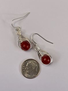 These elegant carnelian drop earrings are striking . The micro faceted surface of these genuine carnelian gemstones really catch the light and sparkles.. The color of these gemstones is burnt orange that is natural and not dyed. I chose to enhance these earrings with a woven silver wire design to let the natural beauty of the stone shine. Featuring an 8mm genuine faceted carnelian gemstone. These earrings are dainty, lightweight and perfect for everyday wear. MATERIALS * Genuine Carnelian Gemsto Carnelian Gemstone Dangle Earrings, Amber Carnelian Gemstone Earrings, Carnelian Drop Earrings With Natural Stones, Carnelian Natural Stone Drop Earrings, Red Carnelian Teardrop Earrings, Red Carnelian Gemstone Earrings, Silver Carnelian Drop Earrings, Amber Carnelian Earrings With Ear Wire, Nickel-free Red Carnelian Earrings