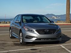 a silver car parked in a parking lot next to the ocean