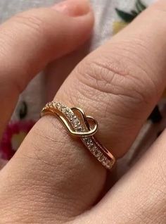 a woman's hand wearing a gold ring with diamonds on the band and a diamond set in the middle