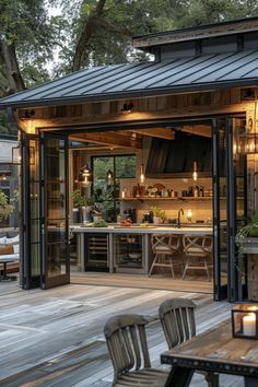 an outdoor kitchen is lit up at night with candles on the table and chairs around it