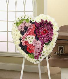 a heart - shaped arrangement of flowers is displayed in front of an open casket with a window behind it