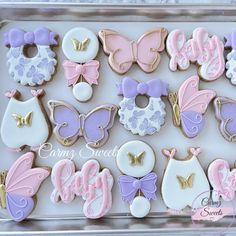 some decorated cookies are in a box on the table and one is pink, purple, white and gold