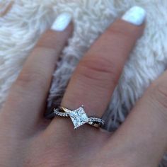 a woman's hand with a diamond ring on top of her finger and white nail polish