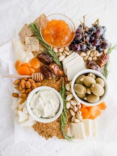 an assortment of cheeses, crackers, nuts and fruit on a platter