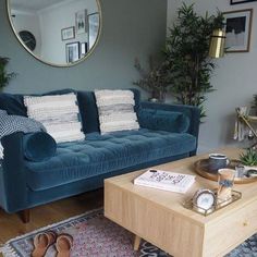 a living room with a blue couch and wooden coffee table in front of a mirror