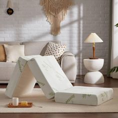 a living room filled with furniture and pillows on top of a carpeted floor in front of a white brick wall