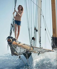 a woman standing on top of a sailboat in the ocean