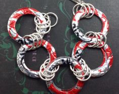 four red and white rings are hanging from silver chains on a black surface with floral designs