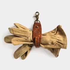 a pair of gloves with a keychain hanging from it's side on a white background