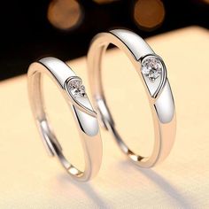 two white gold wedding rings with diamonds on each one, sitting next to each other