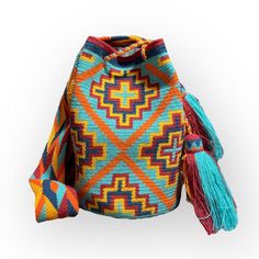 a multicolored bag with tassels on the front and back ends, sitting against a white background