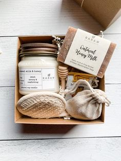 an open box with various items inside on a white wooden surface, including soap and honey