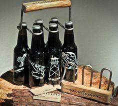 six black beer bottles sitting on top of a wooden table next to a corkscrew