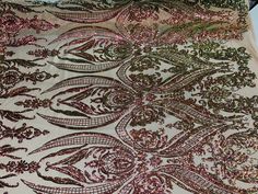 a piece of cloth with pink and green sequins on it, sitting on top of a table