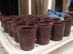 chocolate cups are lined up on a white platter in front of the camera, ready to be eaten