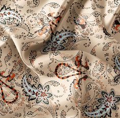 an orange and blue paisley print fabric with black, white, and red designs on it