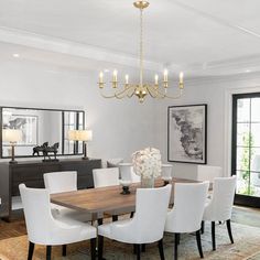 a dining room table with white chairs and a chandelier