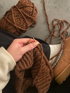 a woman is holding onto her brown knitted scarf and shoes with one hand on the ground