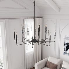 a chandelier hanging from the ceiling in a living room with white walls and curtains