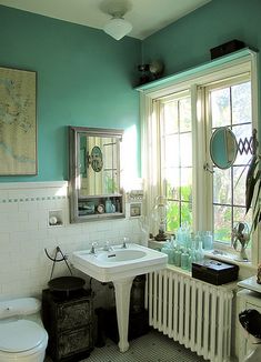 a bathroom with a toilet, sink and radiator next to a large window