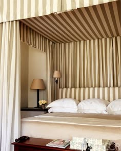 a bed sitting under a canopy next to a table with a lamp on top of it