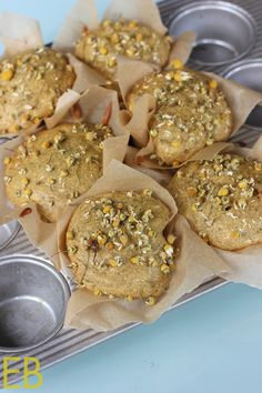 muffins with sprinkles are sitting on wax paper next to tins