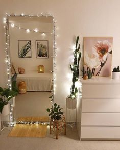 a bedroom decorated in white with lights and plants