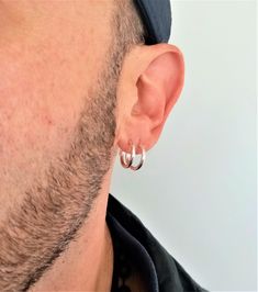 a close up of a man with ear piercings on his ears wearing a hat