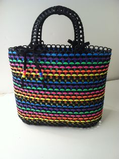 a multicolored woven bag sitting on top of a white table