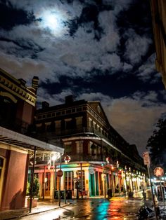 a city street at night with the moon in the sky and buildings on both sides