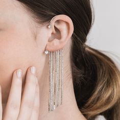 a close up of a person wearing some kind of earring with chains attached to it