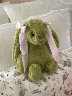 a green stuffed animal sitting on top of a bed