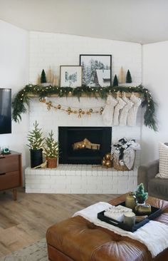 a living room filled with furniture and a fire place covered in christmas garlands next to a flat screen tv