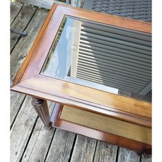 an old wooden table with glass top sitting on a wood flooring area next to a metal grate