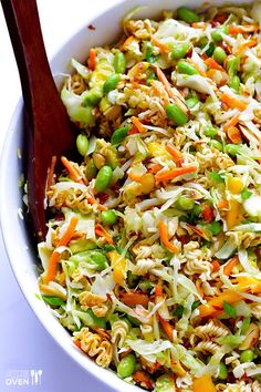 a white bowl filled with rice and vegetables next to a wooden serving utensil