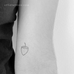 a small strawberry tattoo on the left inner arm, with an outline of a fruit