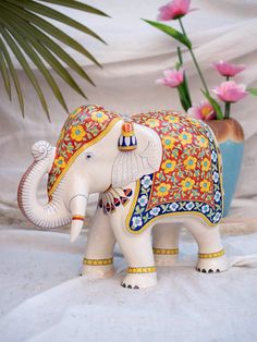 an elephant figurine sitting on top of a table next to some pink flowers