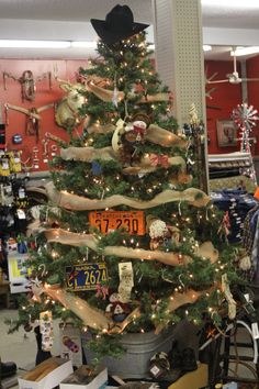 a christmas tree decorated with burlap ribbon and cowboy hats is in a store