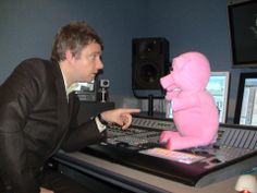 a man sitting in front of a mixing desk with a stuffed animal on top of it