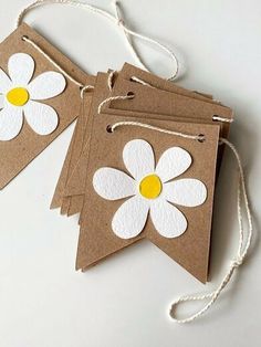 three brown tags with white and yellow flowers on them