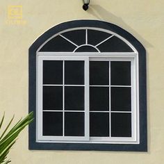 an arched window on the side of a building with potted plants in front of it