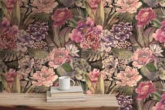 a coffee cup sitting on top of a wooden table next to a flower wallpaper