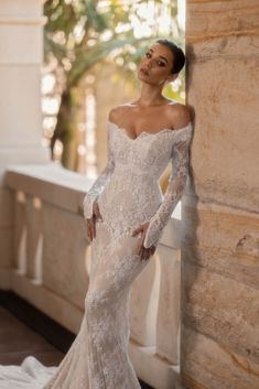 a woman in a wedding dress leaning against a wall