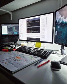 two computer monitors sitting on top of a desk next to a keyboard and monitor screen